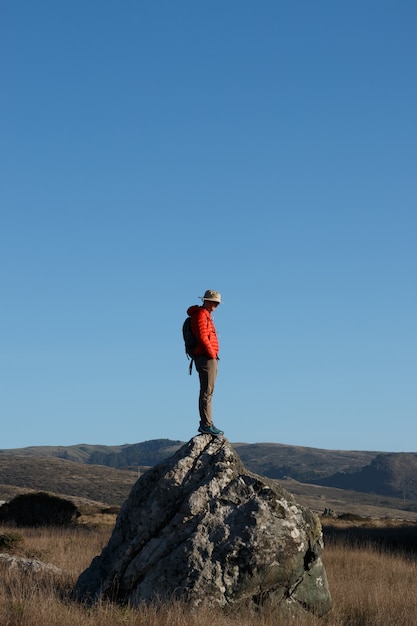 Disparo vertical de un excursionista masculino de pie sobre una piedra en las montañas