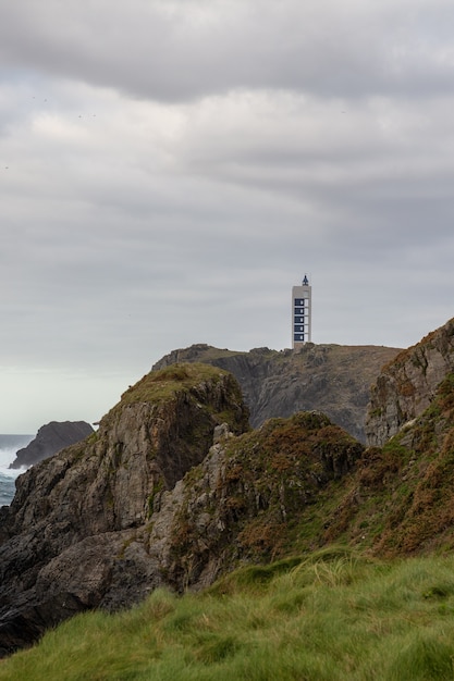 Disparo vertical del faro de Meares en la cima de una montaña en un día nublado en Galicia, España