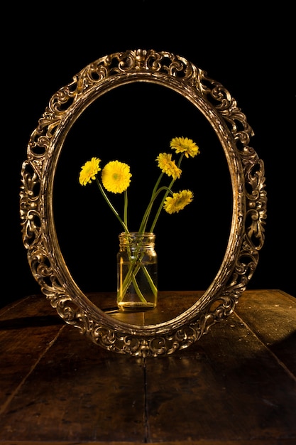 Disparo vertical de flores amarillas en un frasco de vidrio reflejado en el espejo