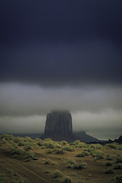 Disparo vertical de una formación rocosa en medio de un paisaje desierto cubierto de niebla