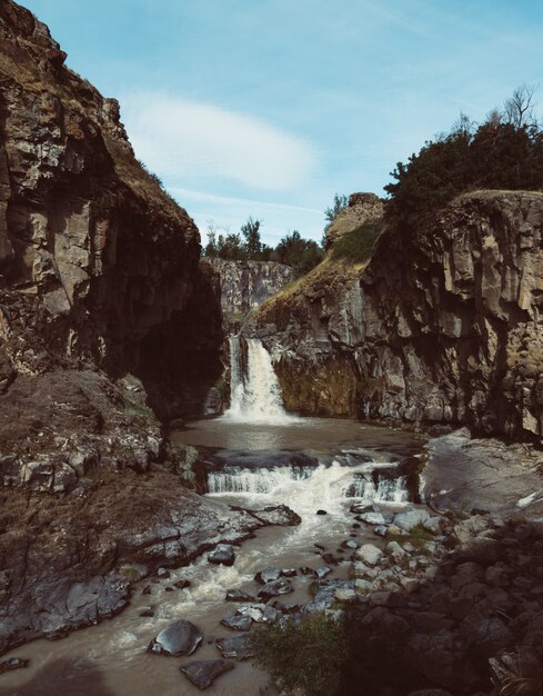 Disparo vertical de una fuerte cascada que fluye en el río entre enormes rocas