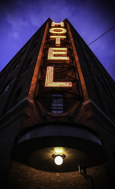 Disparo vertical de un gran edificio con un cartel de hotel y un cielo azul oscuro