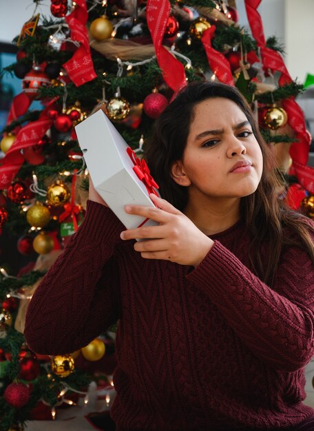 Disparo vertical de una hermosa joven sosteniendo un regalo de Navidad