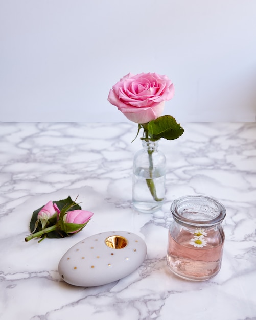 Disparo vertical de una hermosa rosa rosa y objetos florales en una superficie
