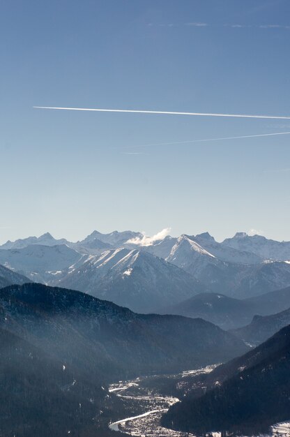 Disparo vertical de hermosas cadenas montañosas bajo un cielo brillante con senderos de motor
