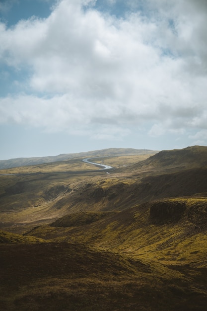 Disparo vertical de las hermosas colinas cubiertas de hierba bajo el cielo nublado capturado en Islandia