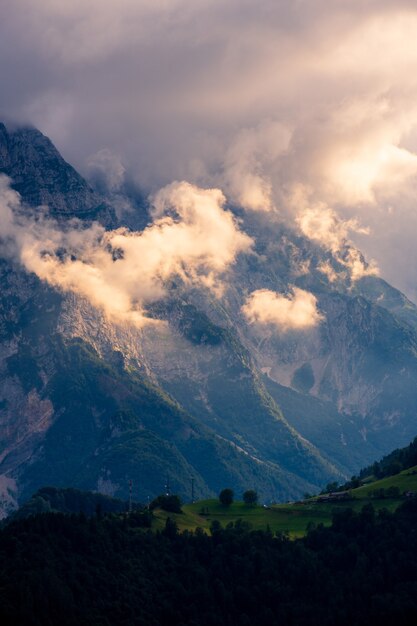 Disparo vertical de hermosas montañas cubiertas de densas nubes y valles verdes