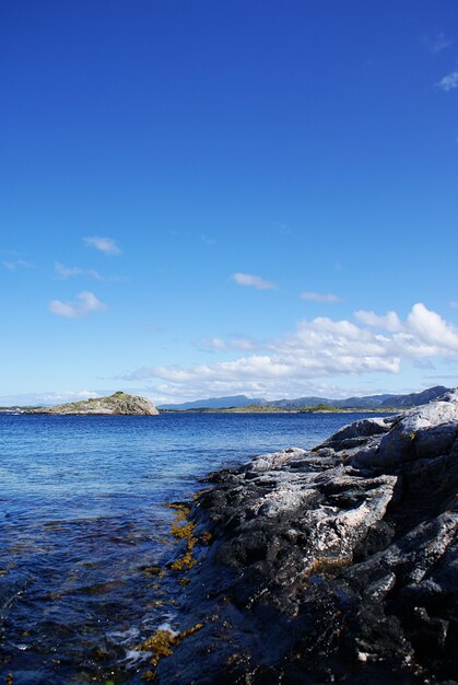 Disparo vertical de un hermoso lago rodeado de acantilados bajo un cielo nublado en Noruega