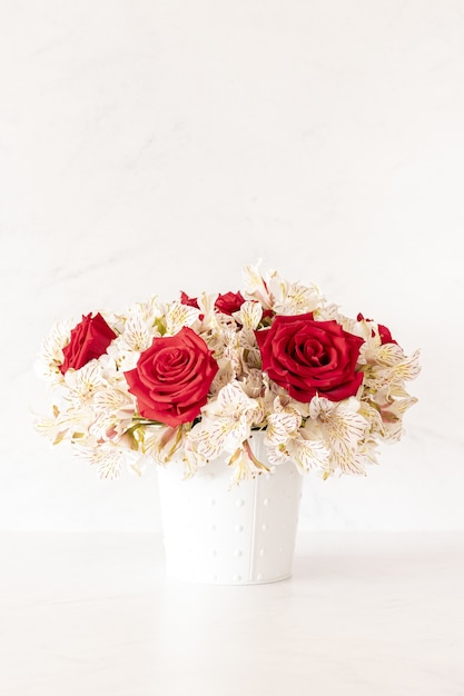 Disparo vertical de un hermoso ramo de rosas rojas y flores de lirio en una caja