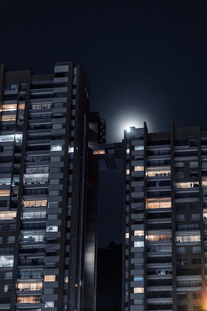 Foto gratuita disparo vertical de hermosos edificios de apartamentos conectados con un pequeño puente bajo el cielo estrellado