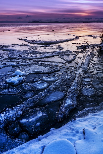 Disparo vertical de hielo y nieve en la playa durante una puesta de sol