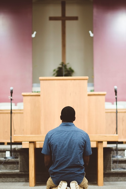 Un disparo vertical de un hombre afroamericano rezando en la iglesia