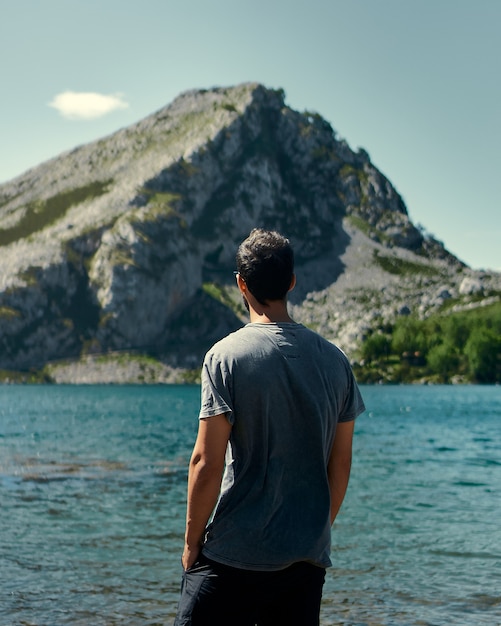 Disparo vertical de un hombre joven mirando un hermoso paisaje marino