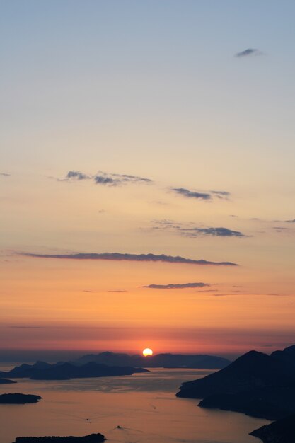 Disparo vertical del horizonte con agua y la puesta de sol en un cielo azul impresionante