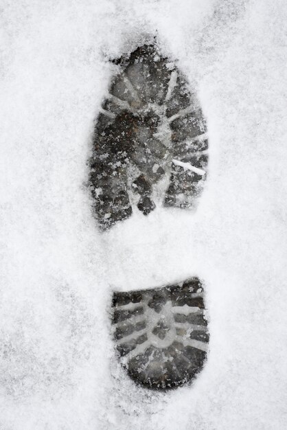 Disparo vertical de una huella de zapato sobre un suelo nevado blanco