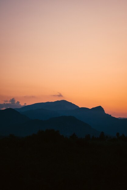 Disparo vertical de una impresionante puesta de sol sobre el bosque rodeado de montañas