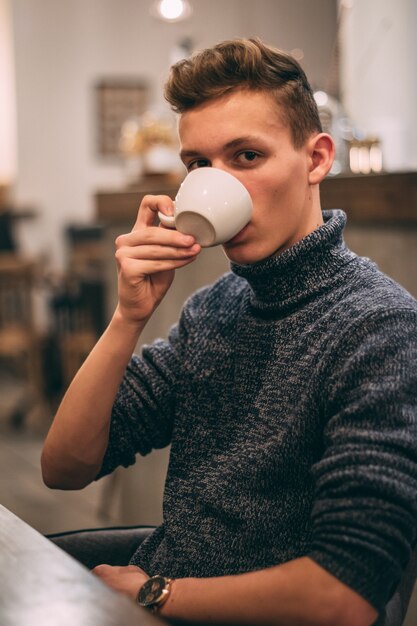 Disparo vertical de un joven bebiendo café en la cafetería