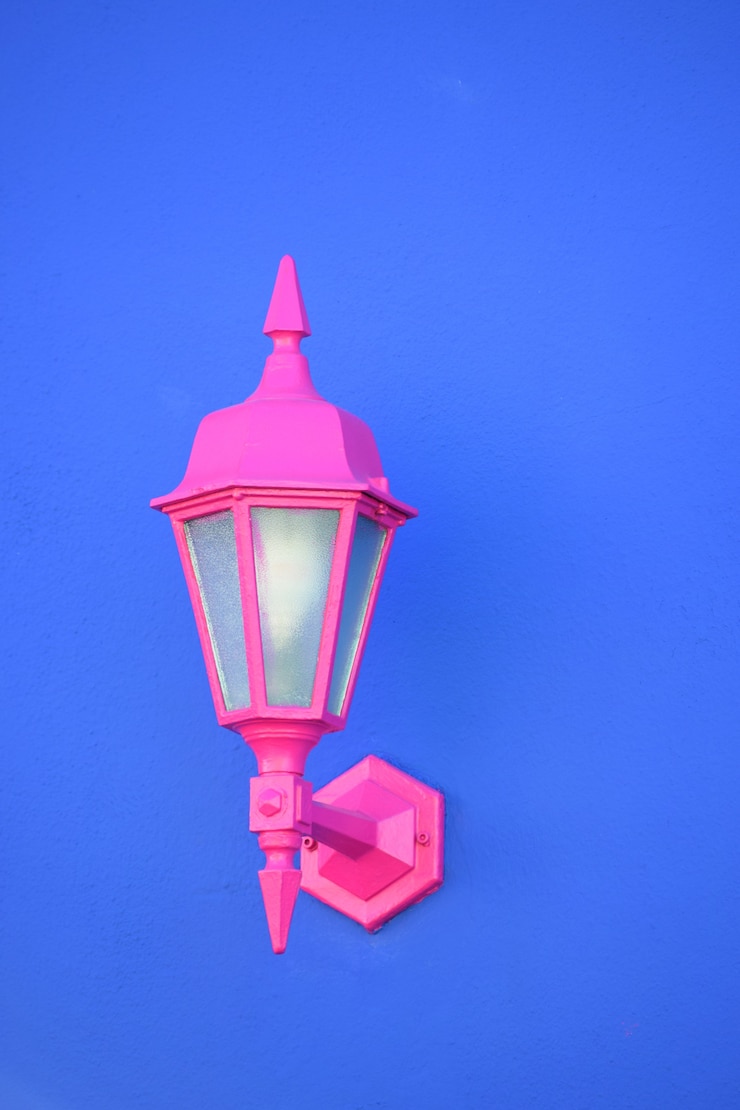 Foto gratuito disparo vertical de una lámpara de pared rosa unida a una pared azul