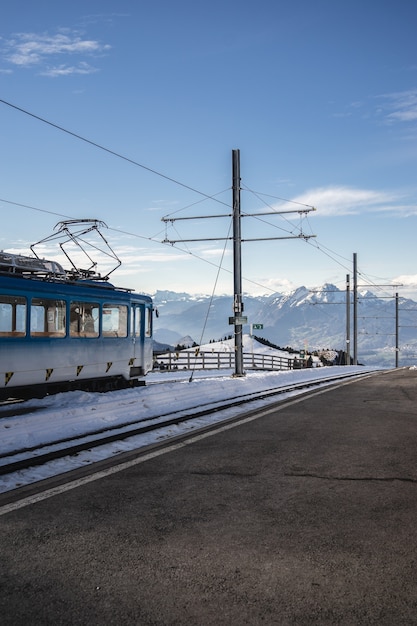 Disparo vertical de una línea aérea junto al ferrocarril de un tren eléctrico bajo un cielo azul claro