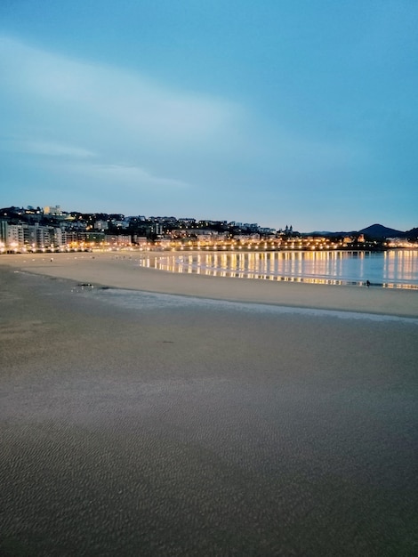 Disparo vertical de las luces de la ciudad reflejándose en el océano en San Sebastián, España