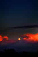 Foto gratuita disparo vertical de la luna y las nubes de fuego en el cielo oscuro