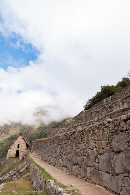 Disparo vertical de Machu Picchu cubierto por nubes en un día soleado