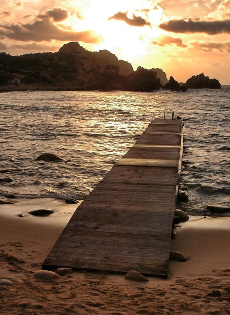 Disparo vertical de un malecón en la playa con la hermosa puesta de sol