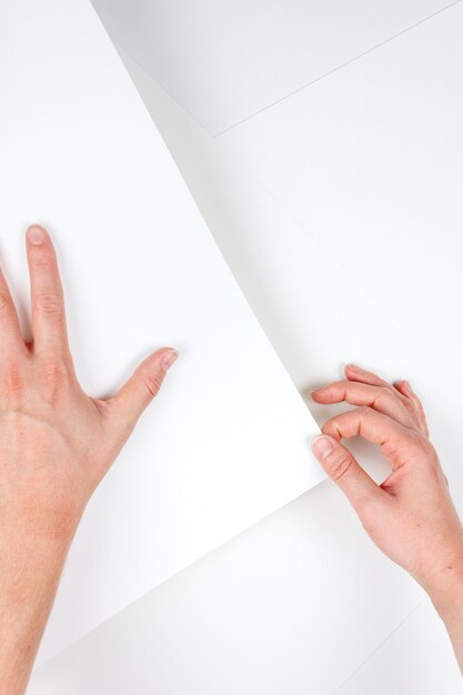 Disparo vertical de manos humanas sosteniendo un trozo de papel blanco