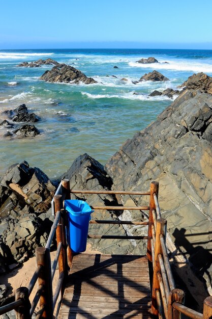 Disparo vertical del mar con olas golpeando las rocas bajo un cielo azul