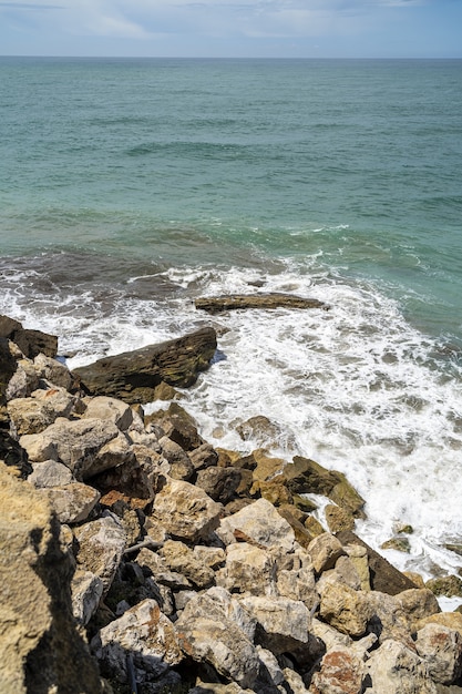 Disparo vertical del mar rodeado por las rocas bajo la luz del sol durante el día