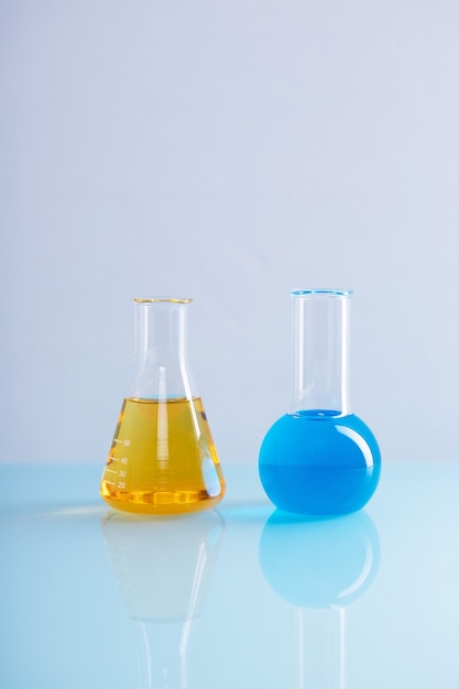 Foto gratuita disparo vertical de matraz erlenmeyer con líquido amarillo y un matraz redondo con líquido azul en un laboratorio