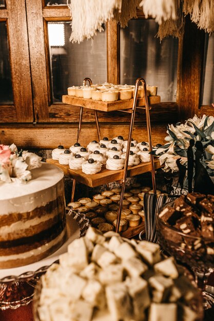 Disparo vertical de una mesa de postres con varios deliciosos pasteles bajo la luz