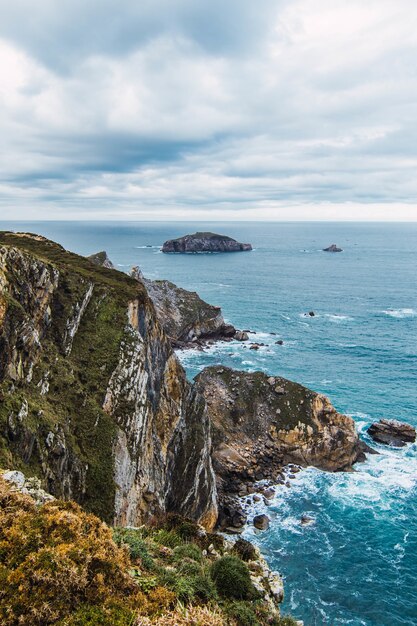 Disparo vertical de las montañas cerca del mar bajo un cielo nublado en Cabo Penas, Asturias, España