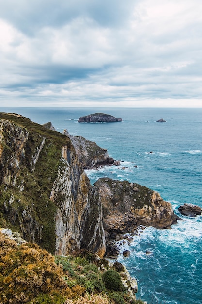 Disparo vertical de las montañas cerca del mar bajo un cielo nublado en Cabo Penas, Asturias, España