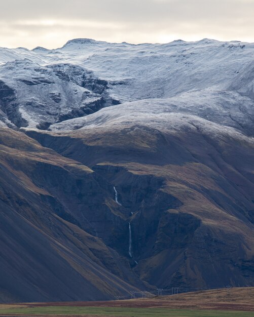Un disparo vertical de montañas con nieve en la parte superior.