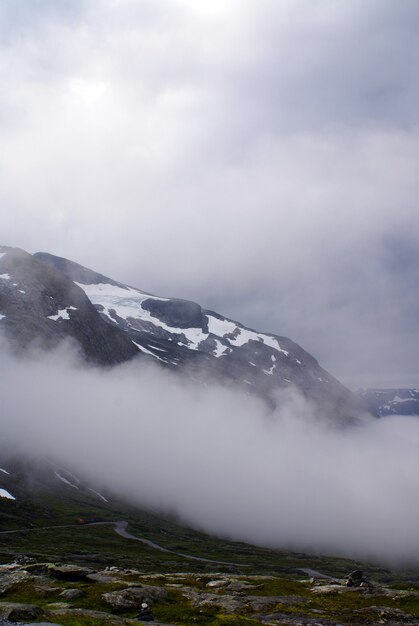 Foto gratuita disparo vertical de montañas rocosas cubiertas de nieve y niebla en noruega