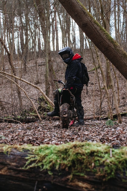 Disparo vertical de un motociclista preparándose para dar un paseo en un bosque