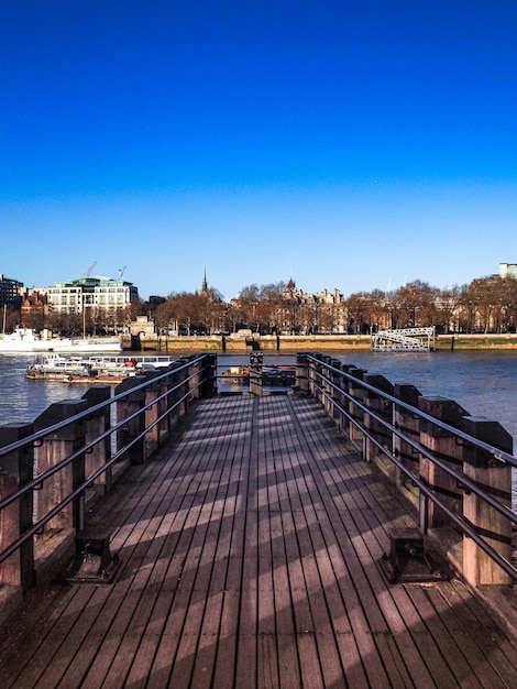 Disparo vertical de un muelle de madera que conduce al río con la ciudad