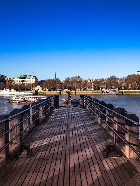 Disparo vertical de un muelle de madera que conduce al río con la ciudad