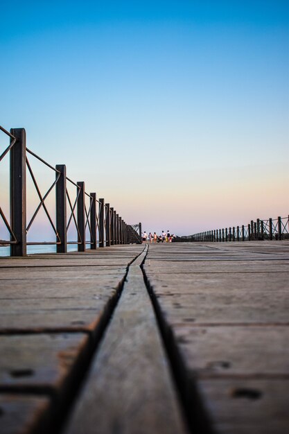 Disparo vertical de un muelle de madera rodeado por vallas bajo el cielo azul de la noche