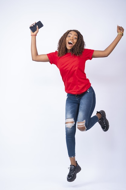 Disparo vertical de una mujer africana feliz saltando de emoción
