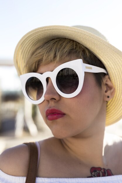 Disparo vertical de una mujer con gafas de sol blancas y un sombrero capturado en la playa