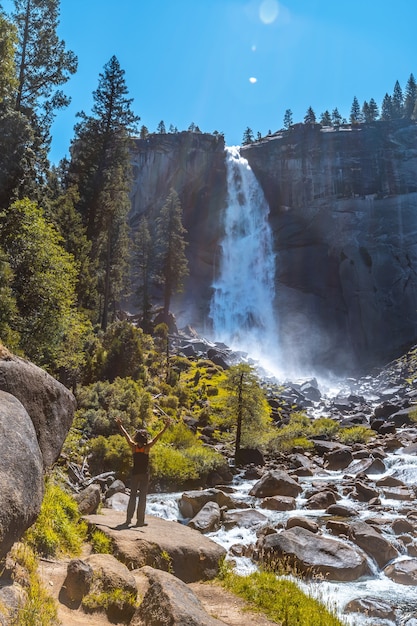 Foto gratuita disparo vertical de una mujer senderismo en la cascada vernal falls del parque nacional yosemite en los ee.