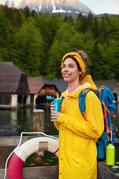 Disparo vertical de mujer sonriente en impermeable amarillo