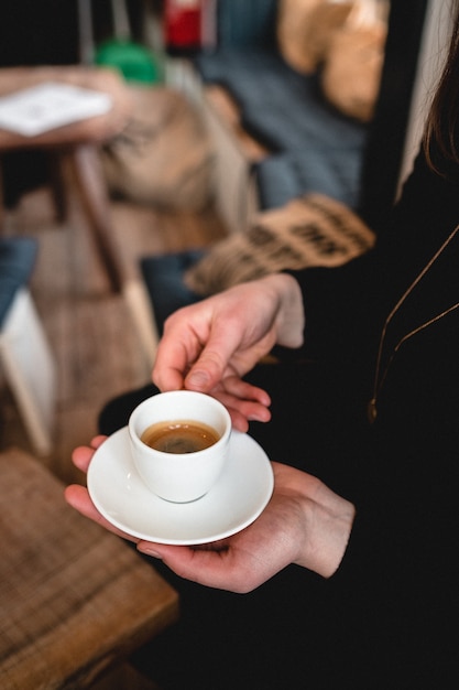 Disparo vertical de una mujer sosteniendo una taza de espresso