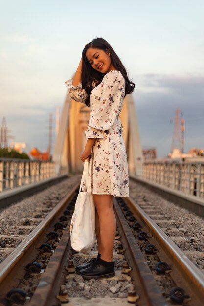 Disparo vertical de una niña vietnamita de pie sobre las vías del tren de un puente viejo