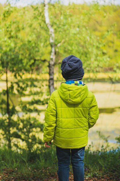 Foto gratuita disparo vertical de un niño con un abrigo amarillo jugando en el patio de recreo