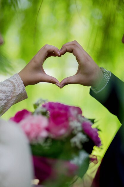 Disparo vertical de la novia y el novio haciendo un corazón con sus manos