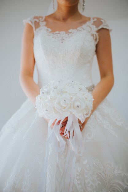 Disparo vertical de la novia vistiendo un hermoso vestido de novia blanco sobre un gris