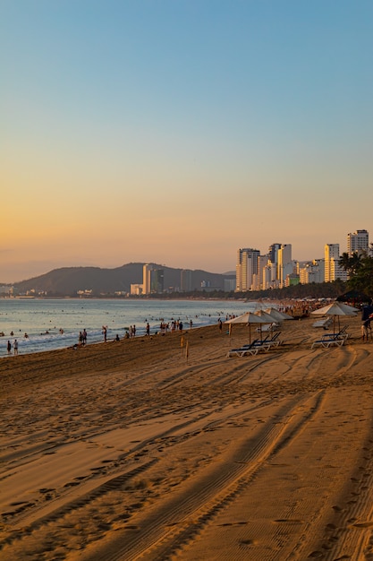 Disparo vertical de la orilla de una playa con gente caminando en Nha Trang